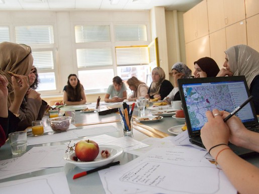 Frauen sitzen um Tisch, diskutieren, arbeiten an Computern