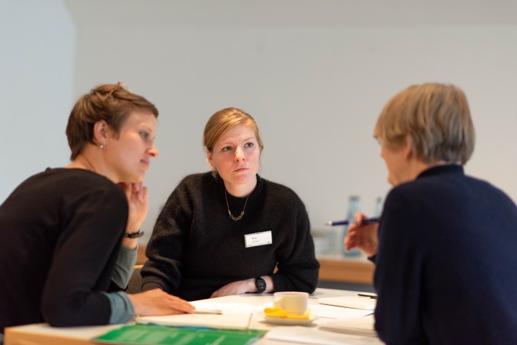 Mehrere Menschen sitzen an einem Tisch und unterhalten sich