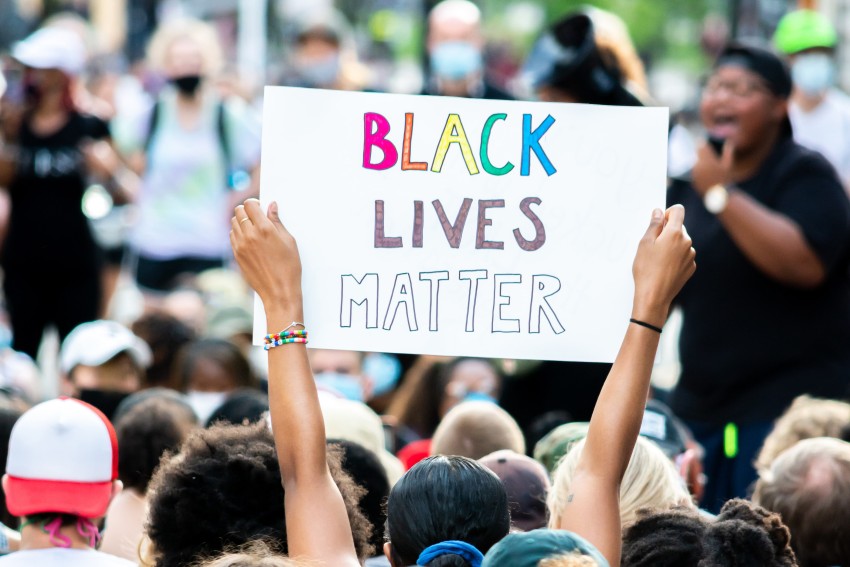 Eine Person hält bei einer Demonstration ein Schild in die Höhe mit der Aufschrift "Black Lives Matter"