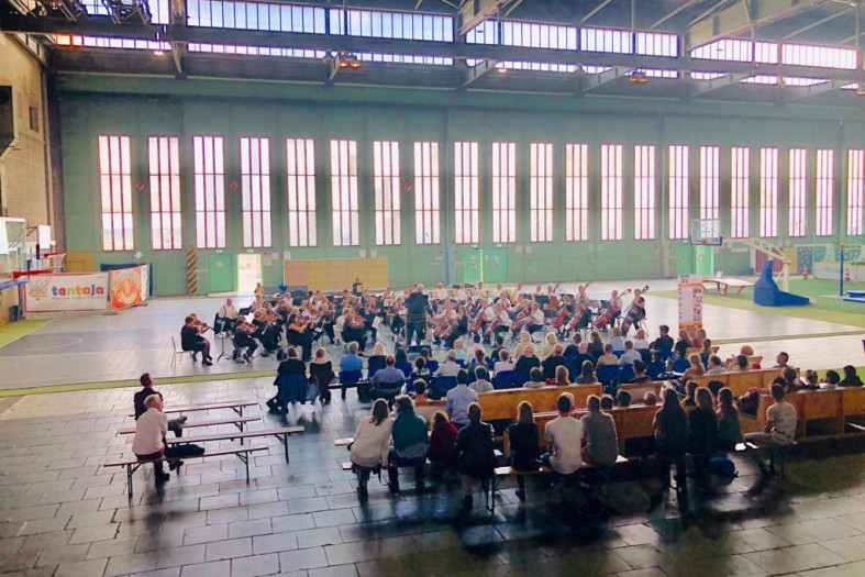 Menschen in einer Halle hören einem Orchester zu