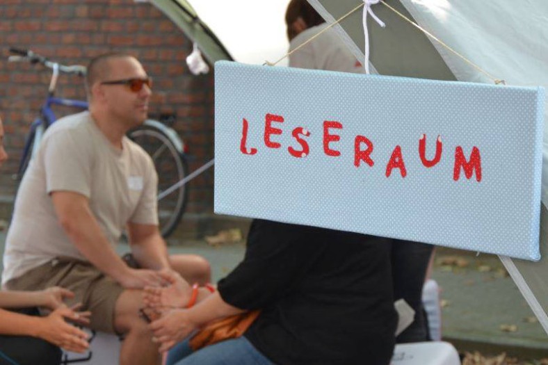 Mann unterhält sich, daneben Schild "Leseraum"