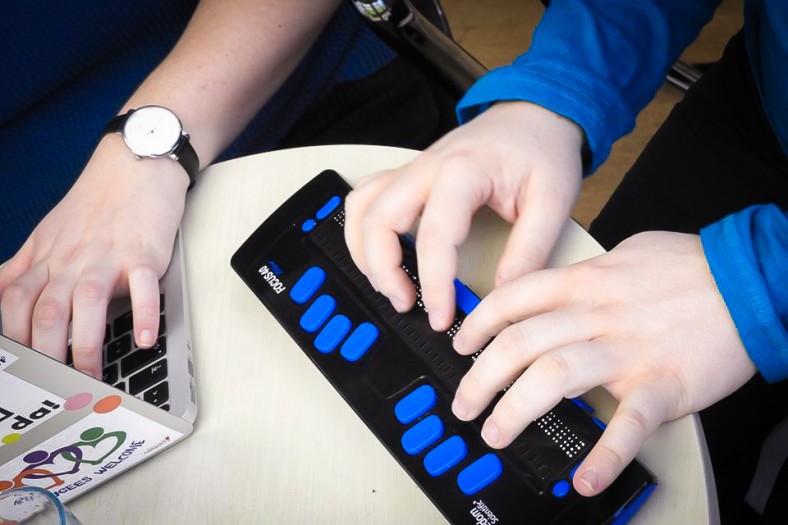 Zwei Personen benutzen einen Laptop inklusive Braillezeile, Ansicht von oben