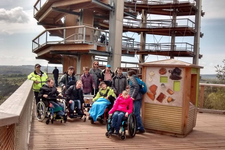 Verschiedene Menschen bei einem Ausflug vor einem Aussichtspunkt, Gruppenfoto