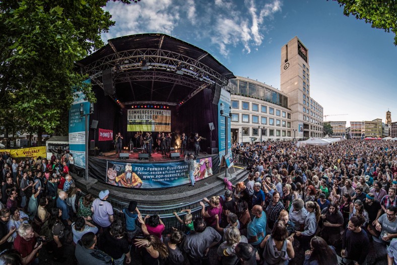 Öffentlicher Platz in Stuttgart mit hunderten Zuschauer*innen, in der Mitte eine Bühne
