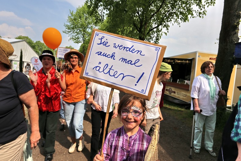 Verschiedene Menschen bei einer Demo, im Vordergrund Mädchen mit Schild